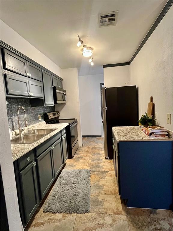 Kitchen with stainless steel appliances, backsplash, gray cabinets, light stone countertops, and a textured wall