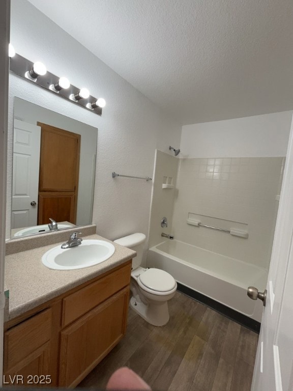 Full bathroom with wood finished floors, vanity, a textured ceiling, and tub / shower combination