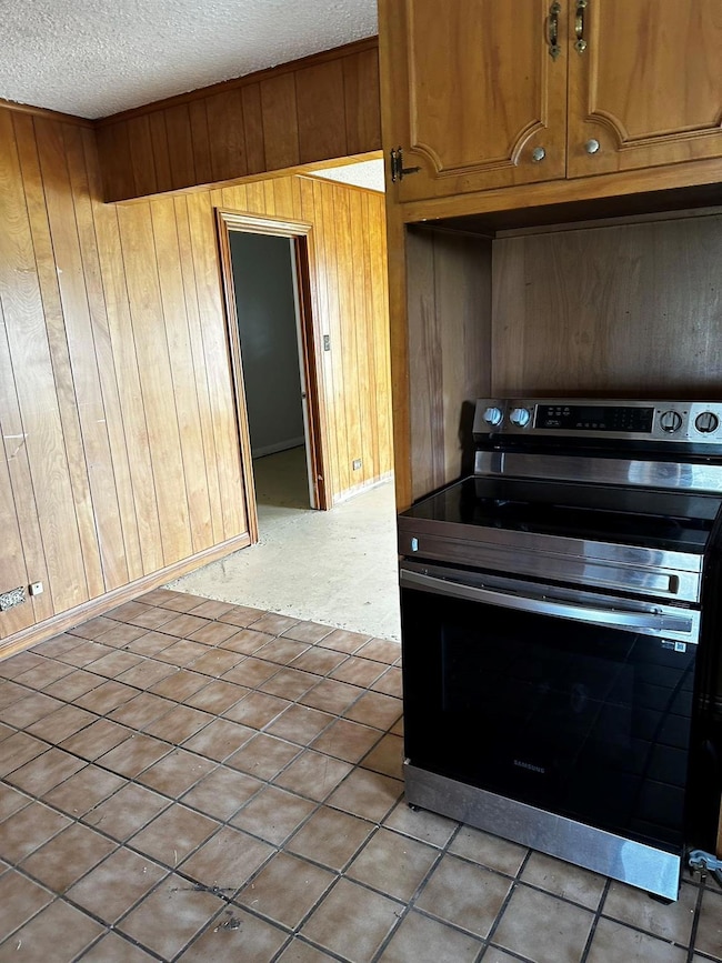 Kitchen with a textured ceiling, light tile patter