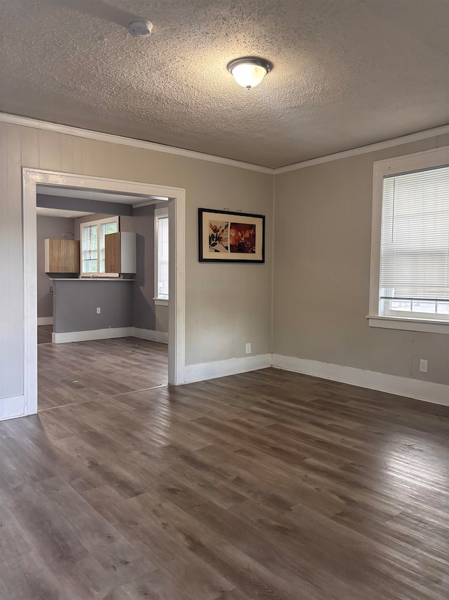 Spare room with a textured ceiling, ornamental molding, wood finished floors, and a smoke detector