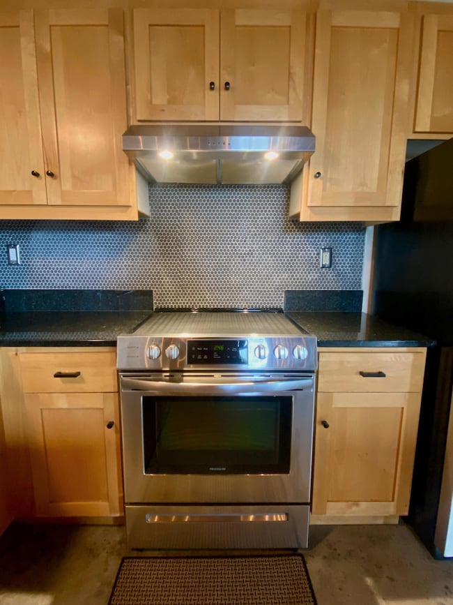 The full-sized electric range top includes a protective cover, two adjacent work spaces, and ventilation from a coordinated range hood.