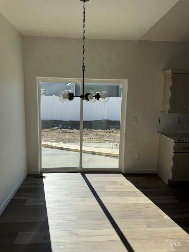 Unfurnished dining area with dark wood finished floors and a chandelier