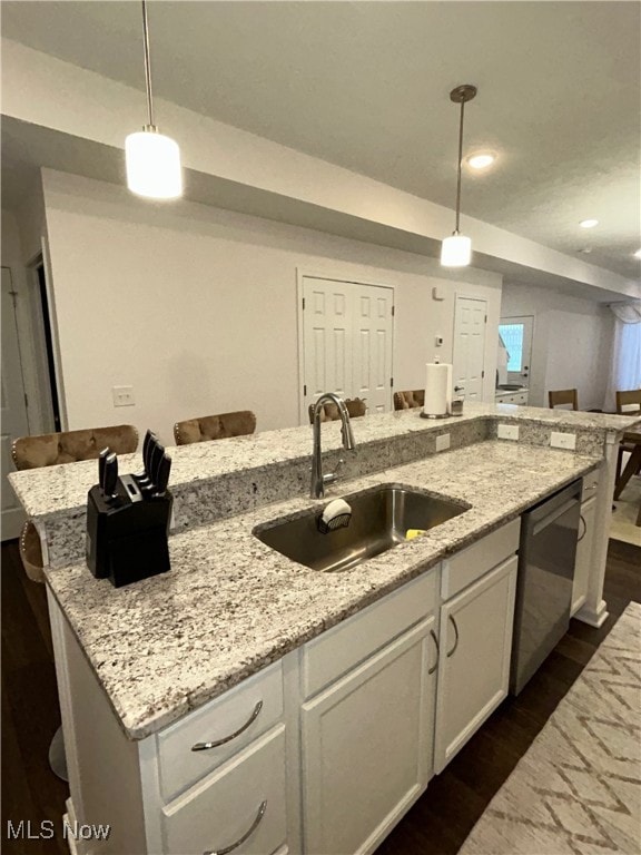 Kitchen with white cabinetry, dark wood-type flooring, a breakfast bar, light stone countertops, and recessed lighting
