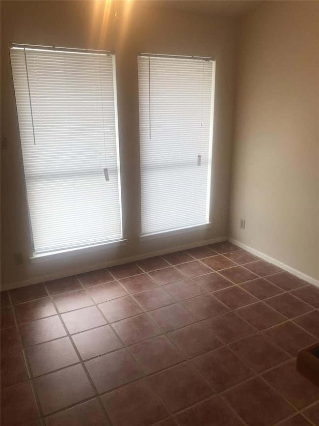 Spare room featuring baseboards and dark tile pat