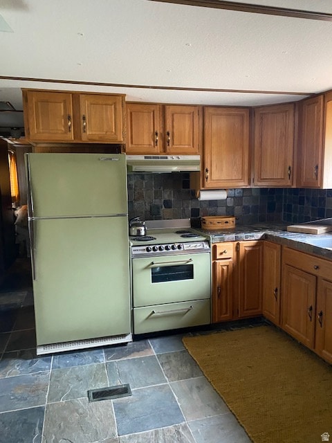 Kitchen with brown cabinets, freestanding refrigerator, range with electric cooktop, tasteful backsplash, and under cabinet range hood