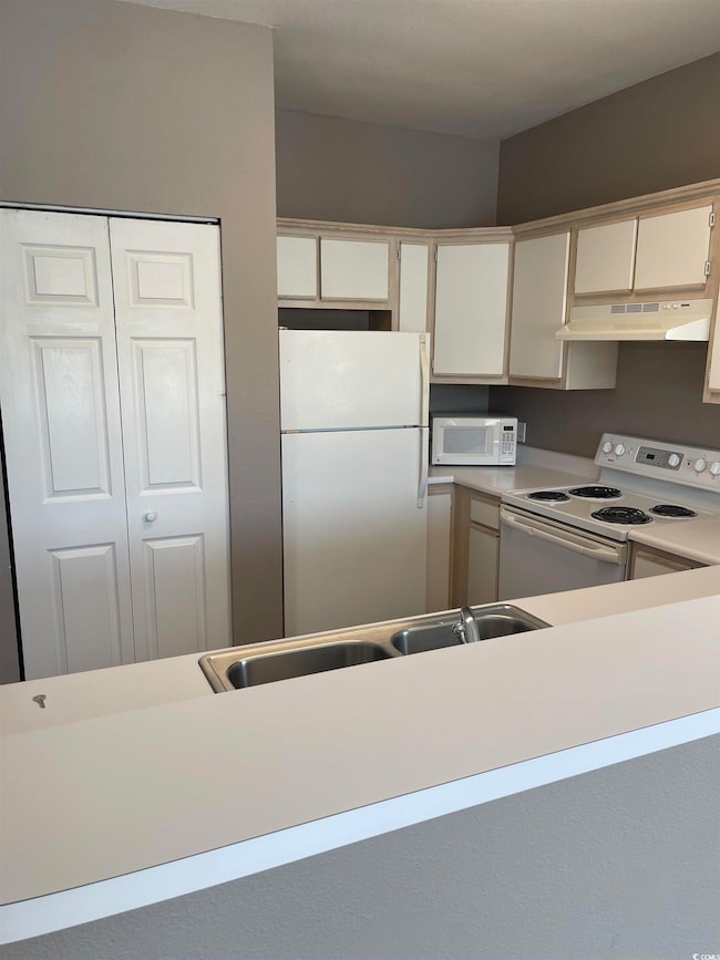 Kitchen featuring white cabinets, a sink, white ap