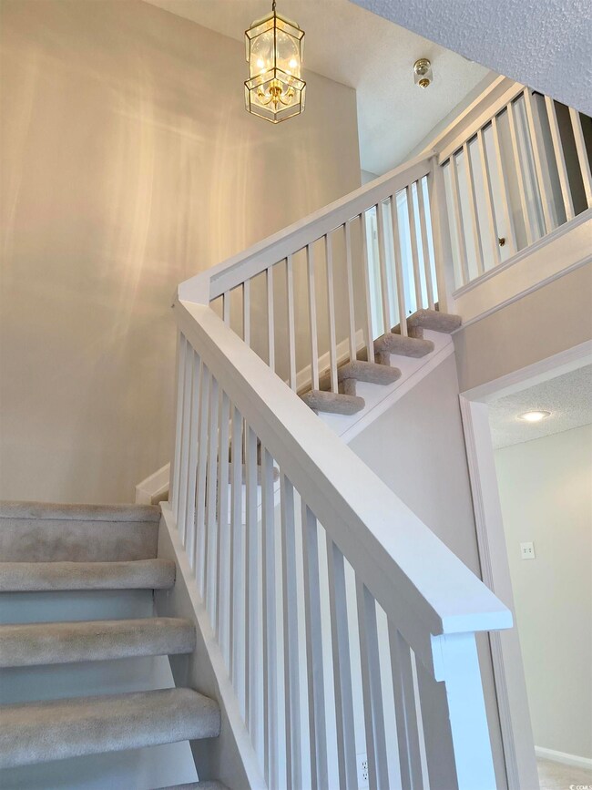 Stairs with an inviting chandelier and a towering ceiling