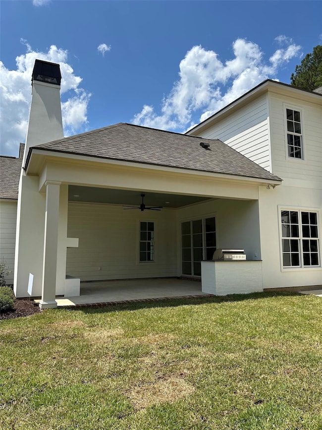 Rear view of property featuring a yard, ceiling fa