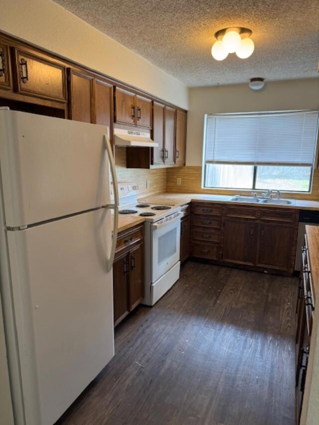 Kitchen with a sink, white appliances, a textured
