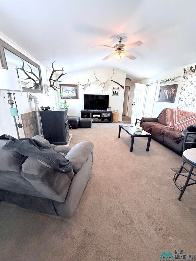 Carpeted living room with vaulted ceiling and a ceiling fan
