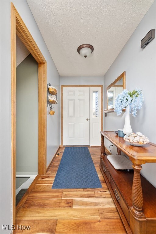 Entrance foyer with light wood-style flooring and a textured ceiling
