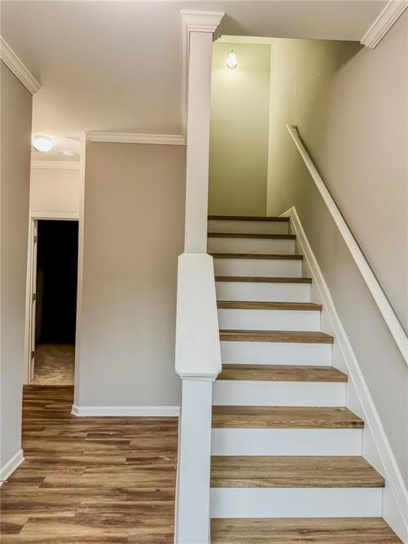Staircase featuring ornamental molding and wood finished floors