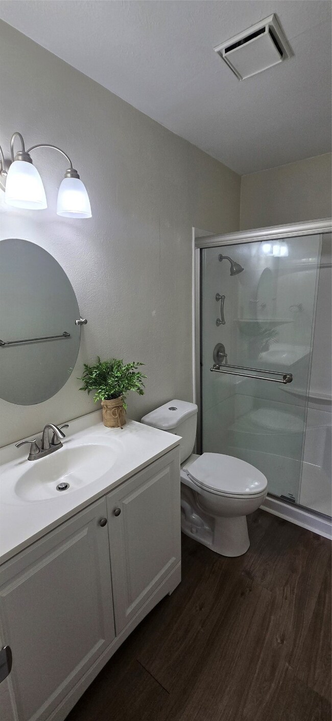Full bathroom featuring wood finished floors, vanity, and a shower stall