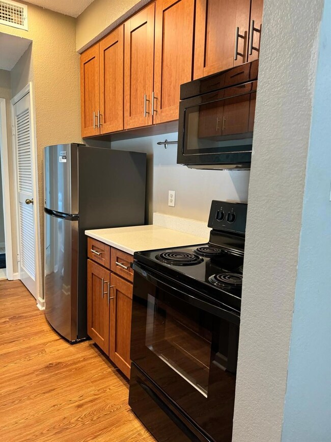 Kitchen with black appliances, brown cabinets, li