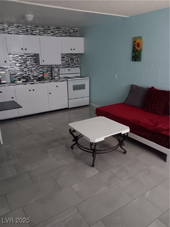 Living area featuring concrete block wall, a textured ceiling, and marble finish floor
