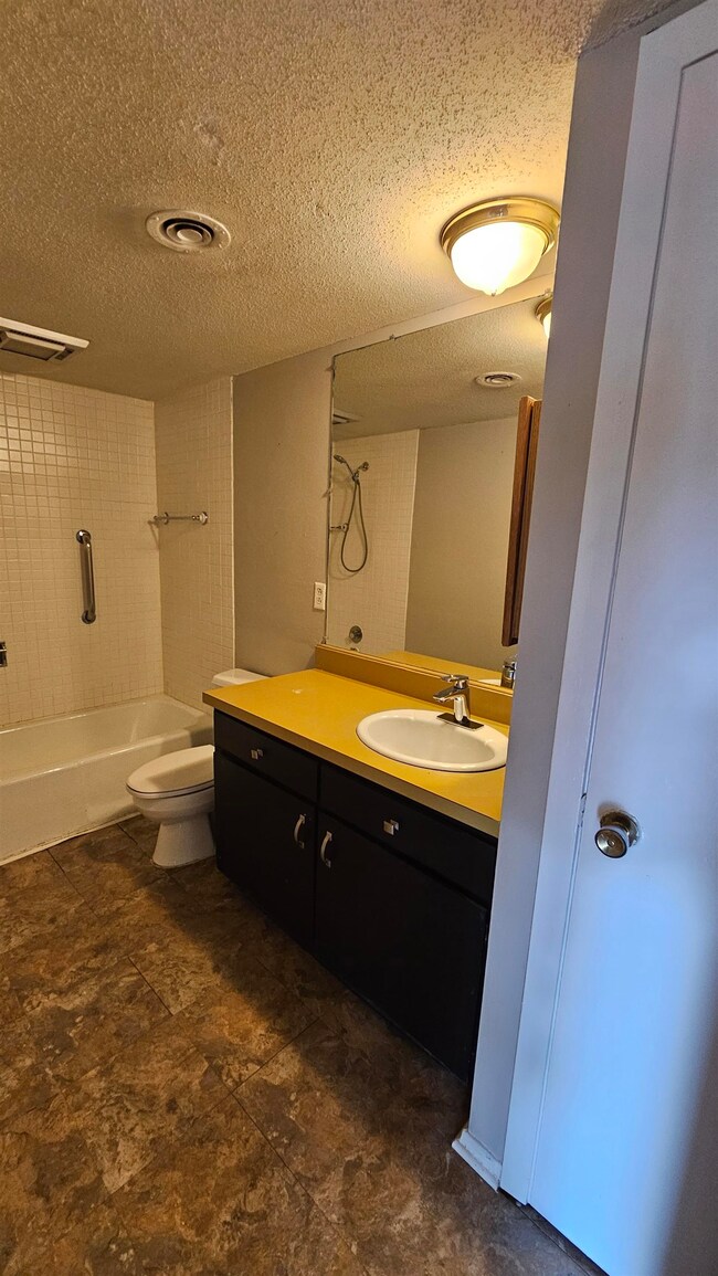Bathroom with vanity, bathing tub / shower combination, and a textured ceiling
