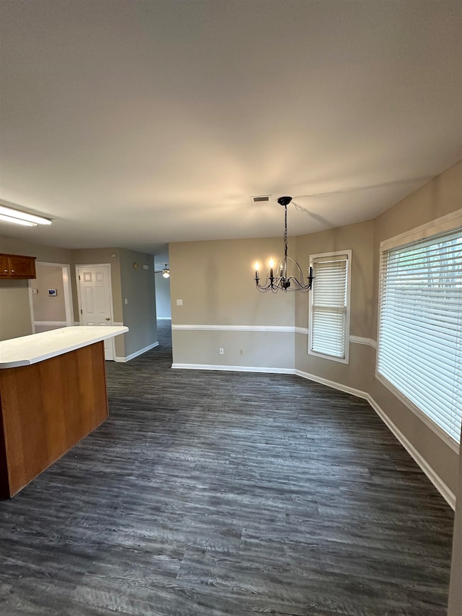 Unfurnished dining area with dark wood finished floors and a chandelier