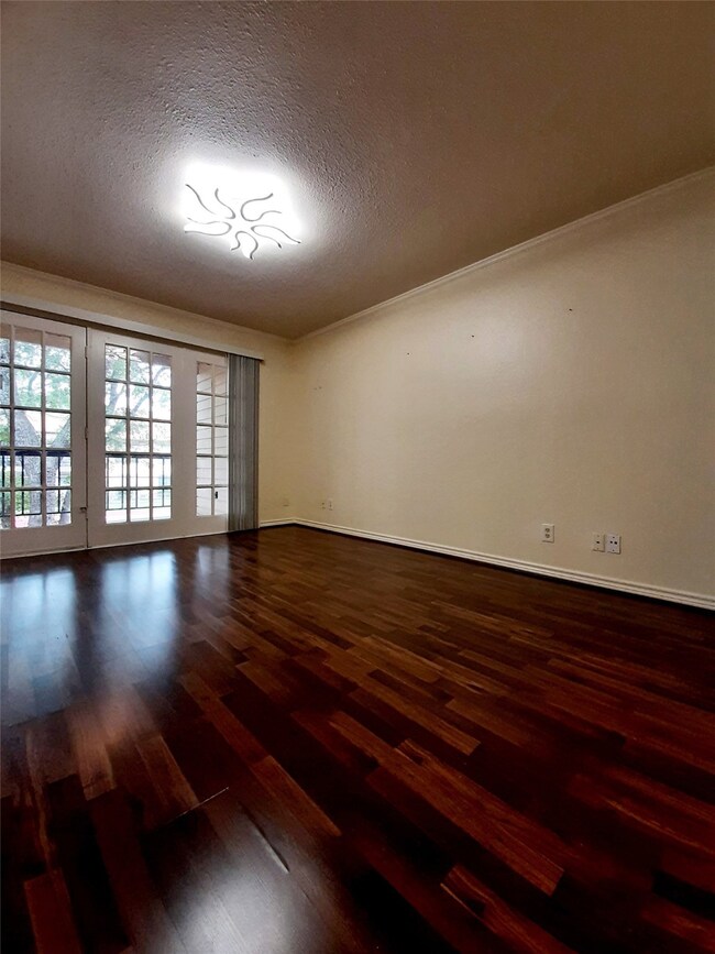 Living room with dark wood finished floors, a textured ceiling, and ornamental molding