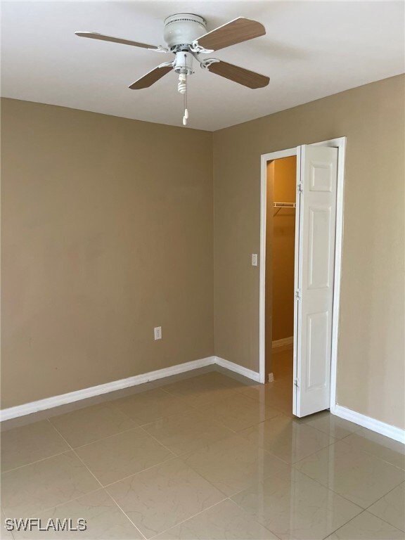Spare room featuring ceiling fan, tile patterned f