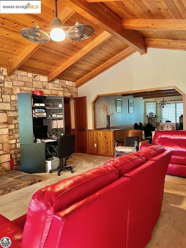 Living room with lofted ceiling with beams, carpet flooring, and wooden ceiling