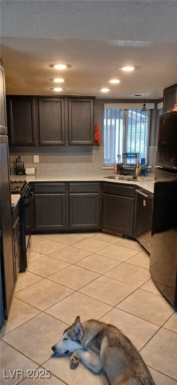 Kitchen with black appliances, light tile patterne