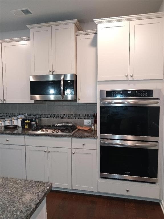 Kitchen with tasteful backsplash, white cabinetry,