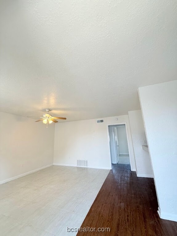 Unfurnished room featuring a textured ceiling, ceiling fan, and wood finished floors