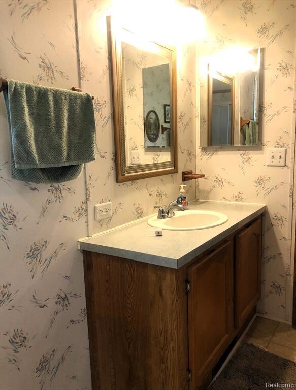 Bathroom featuring vanity, wallpapered walls, and tile patterned flooring