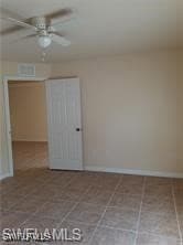Tiled spare room with ceiling fan and baseboards