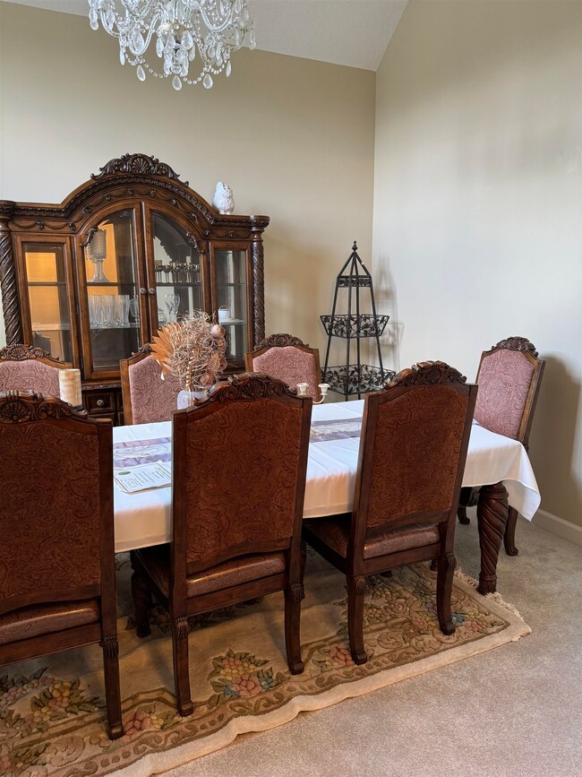 Carpeted dining room featuring lofted ceiling and 