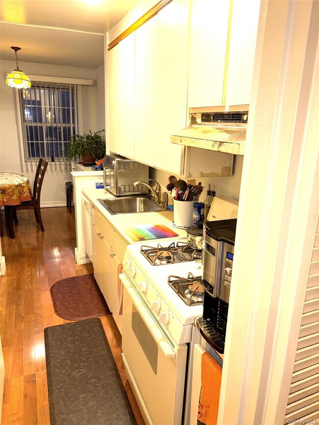 Kitchen with gas range gas stove, light countertops, hanging light fixtures, ventilation hood, and dark wood finished floors