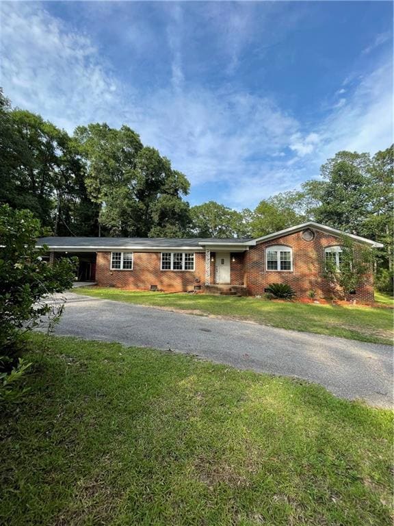 Single story home featuring driveway, brick siding, and a front yard