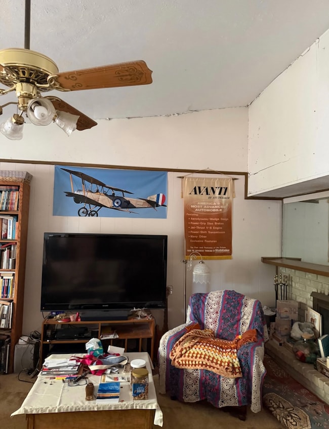 Living area featuring carpet flooring, a fireplace, and ceiling fan