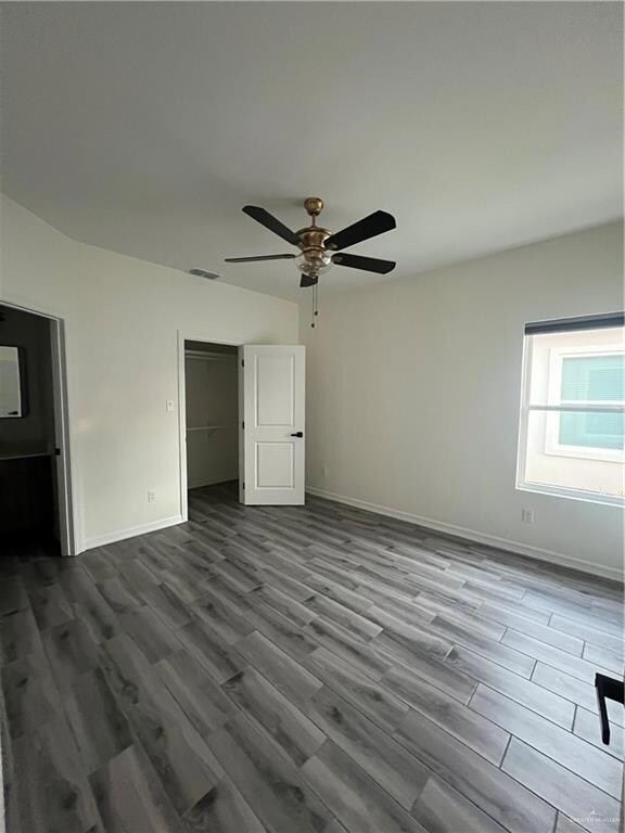 Unfurnished bedroom featuring dark wood finished floors, a closet, and a ceiling fan