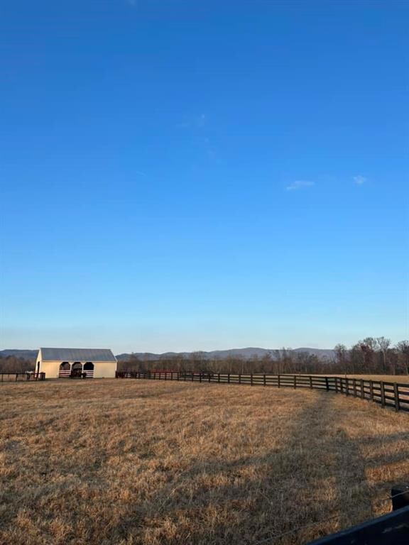 View of yard featuring fence, a view of rural / pastoral area, an outdoor structure, and a mountain view