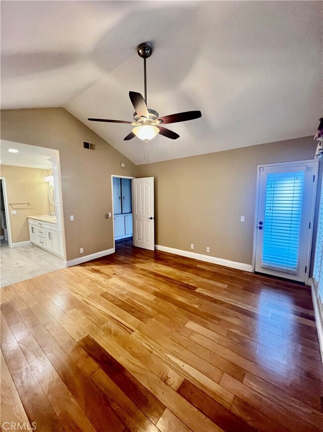 Another view of downstairs master shows it also has a door into front courtyard, wood floors, ceiling fan and spacious master bath