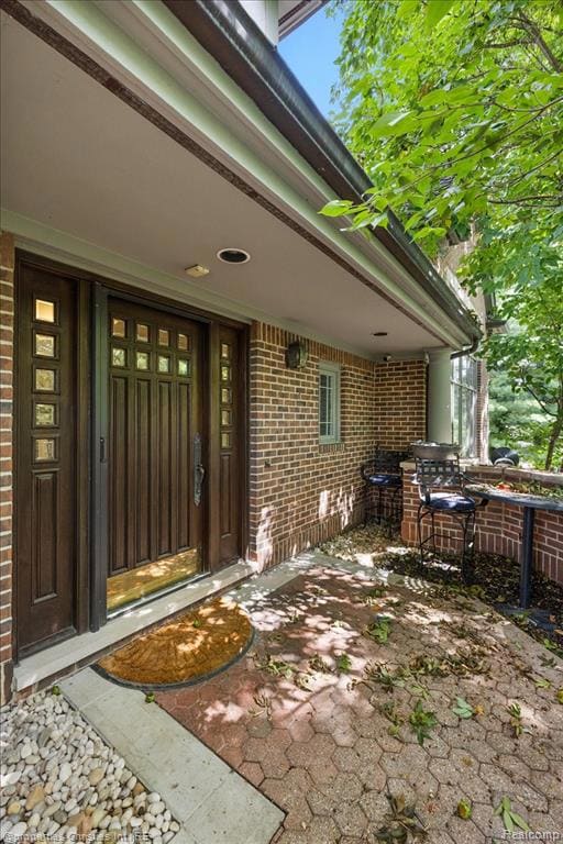 Doorway to property featuring brick siding and a patio area