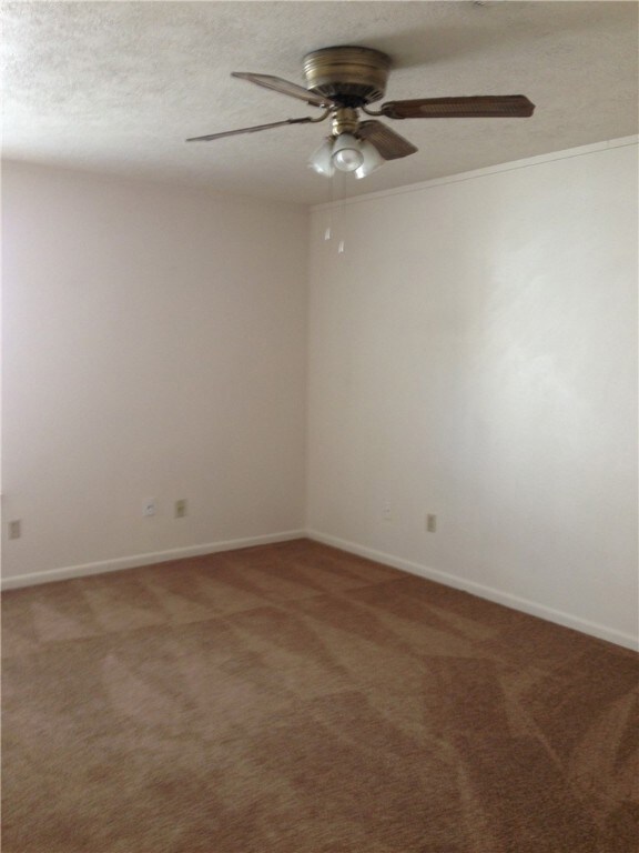 Spare room featuring ceiling fan, carpet, and a textured ceiling