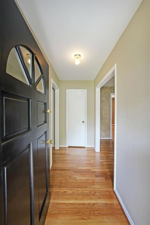 Corridor featuring light wood-type flooring and baseboards