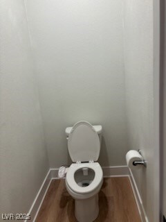 Bathroom featuring toilet, baseboards, and wood fi
