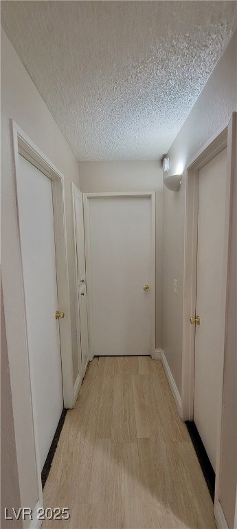 Hall featuring light wood finished floors and a te