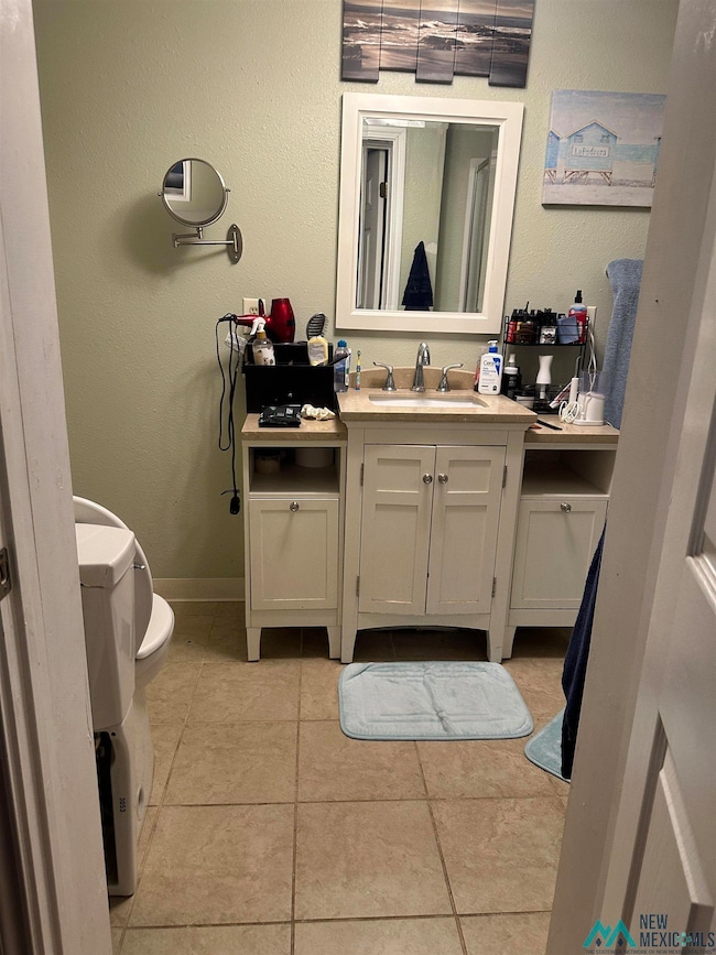 Bathroom with a textured wall, vanity, and light tile patterned floors