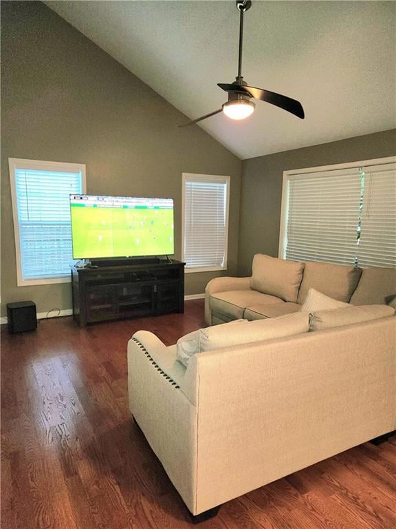 Living room with lofted ceiling, dark wood-type flooring, and a ceiling fan