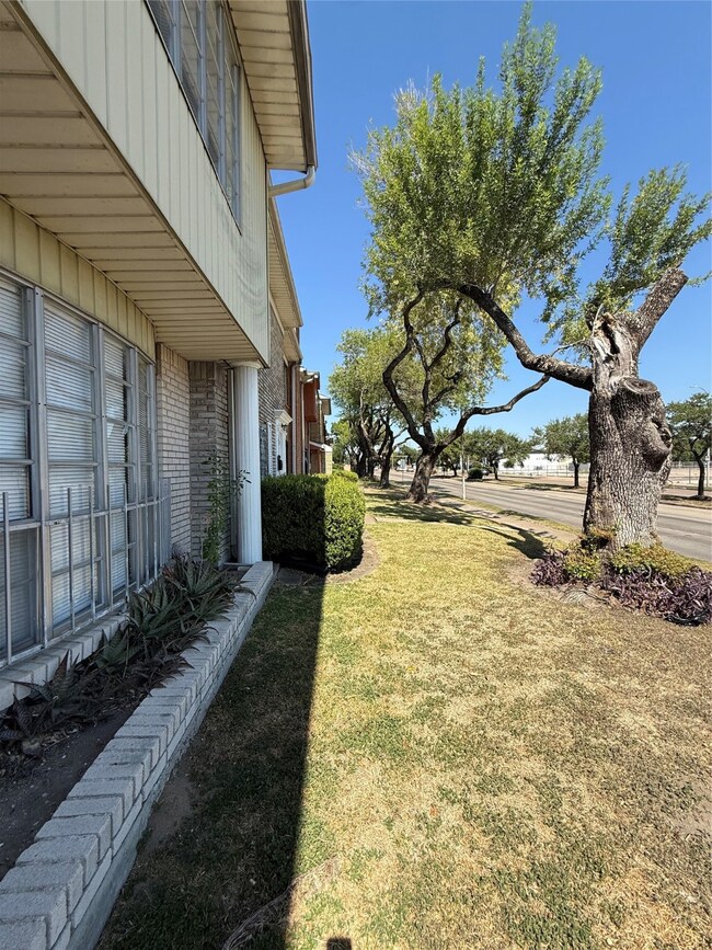 Charming home exterior with a well-maintained lawn and mature trees lining the street. Brick and siding facade offers a classic look, complemented by large windows and tidy landscaping. Quiet, tree-lined neighborhood.
