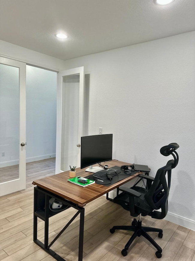 Office space featuring light wood-type flooring, recessed lighting, and french doors
