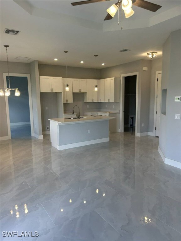 Kitchen featuring hanging light fixtures, light marble finish floors, a kitchen island with sink, recessed lighting, and ceiling fan