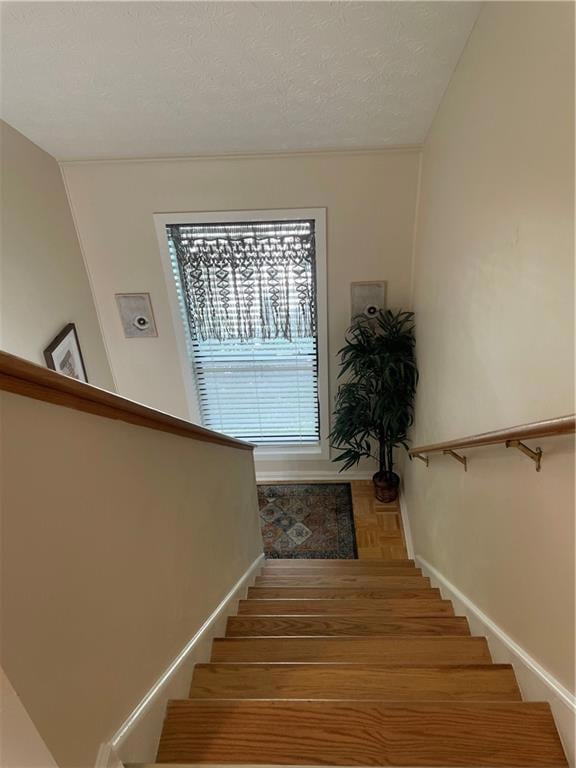 Staircase with a textured ceiling and baseboards