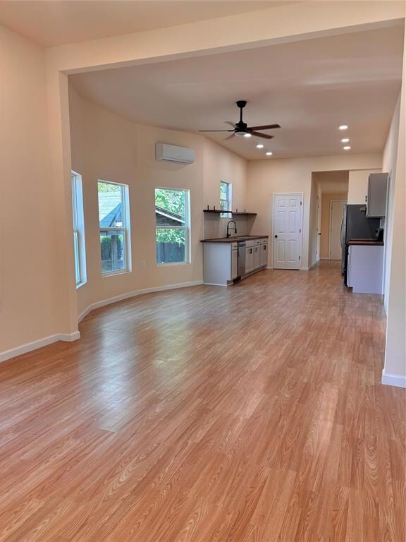 Unfurnished living room with ceiling fan, light ha