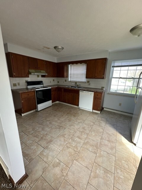 Kitchen with sink, white appliances, light tile flooring, and tasteful backsplash