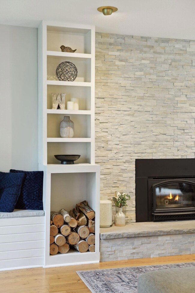 The beautiful stone fireplace with newer wood burning insert is flanked by built-in feature shelves and wood box.
